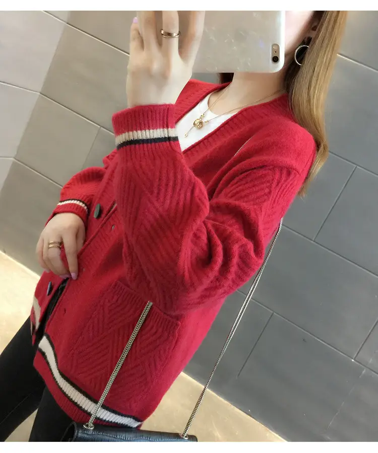 Angled view of red cardigan showing textured sleeve, striped cuff and front pocket.