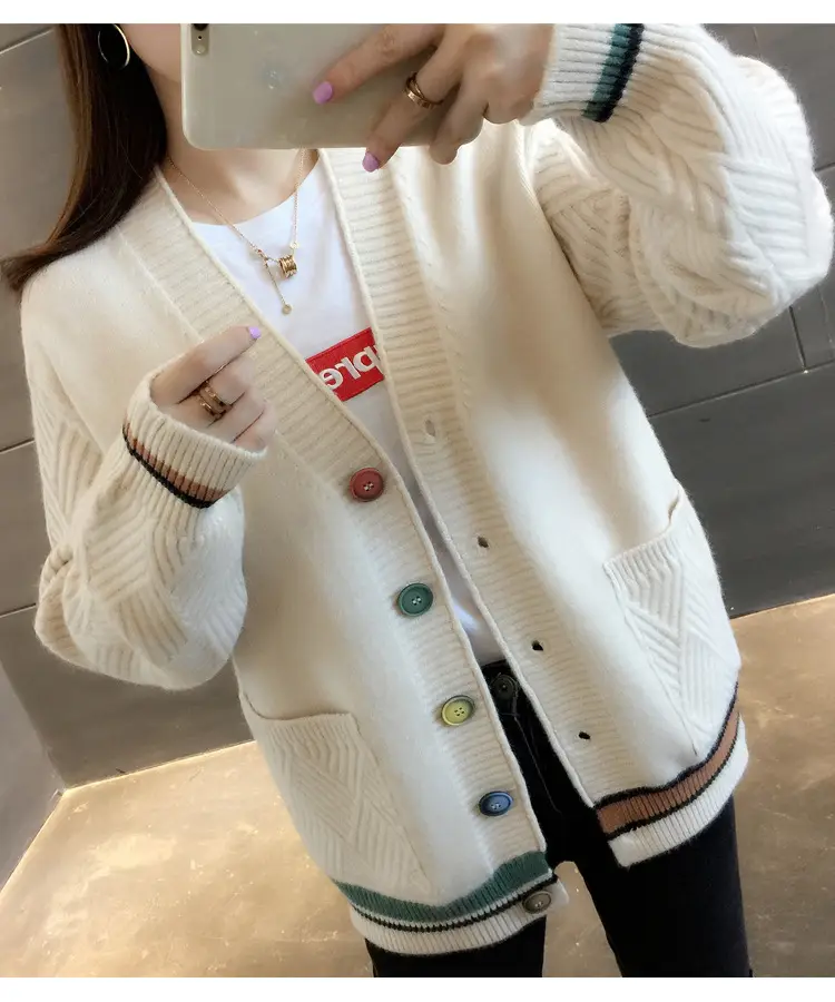 Close view of the white cardigan's V-neck, buttons, textured sleeves and striped hem.