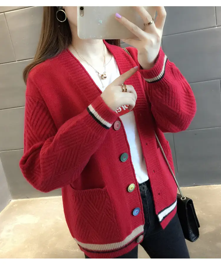 Angled front view of red cardigan with V-neck, textured sleeves and patch pockets.